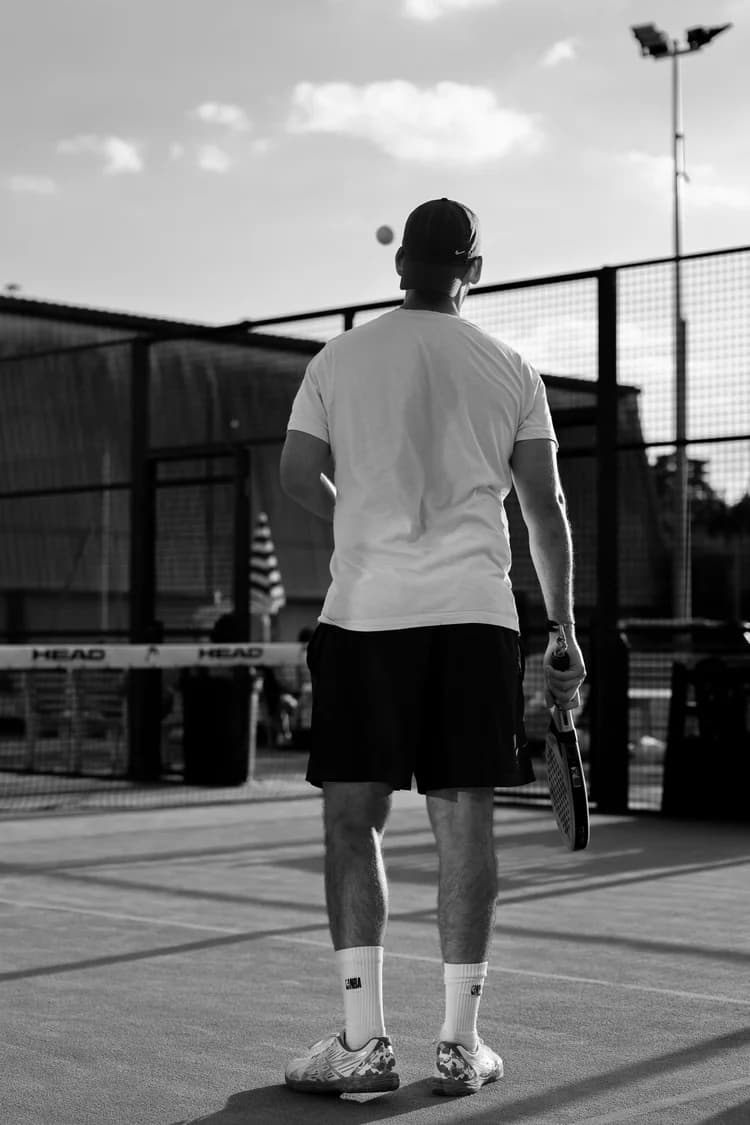 Court de padel en fin de journée, joueur de dos face au filet